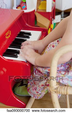 Stock Image - Little girl playing toy piano, cropped. Fotosearch