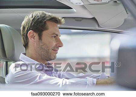 Stock Image - Man driving car, smiling. Fotosearch