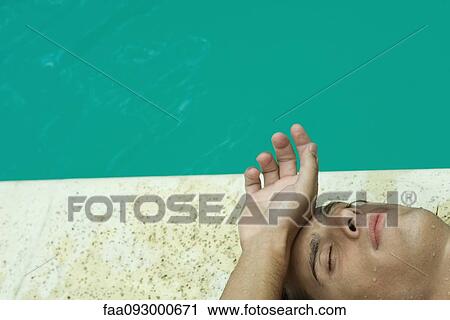 Man lying on back next to pool, touching forehead with back of hand View Large Photo Image Stock Image - Man lying on back next to pool, touching forehead with back of hand. Fotosearch
