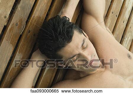 Man reclining on wet deck with hands behind head, high angle view View Large Photo Image Stock Photography - Man reclining on wet deck with hands behind head, high angle view. Fotosearch