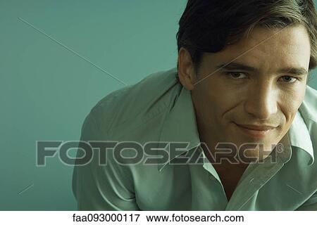Stock Photo - Man smiling, leaning forward, looking at camera. Fotosearch
