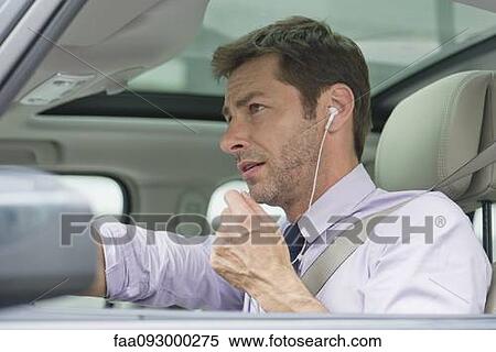 Stock Photography - Man using earphone headset while driving. Fotosearch