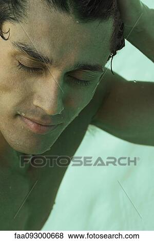 Man with hand on head, eyes closed, water in background View Large Photo Image Stock Photo - Man with hand on head, eyes closed, water in background. Fotosearch