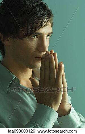 Stock Photograph - Man with hands clasped in prayer, close-up. Fotosearch