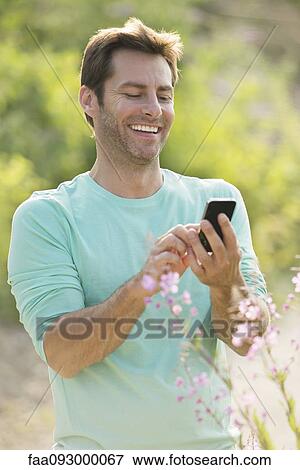 Stock Photo - Mature man using cell phone while enjoying the great outdoors. Fotosearch
