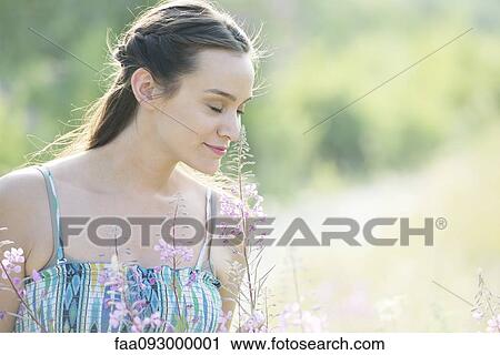 Stock Image - Mid-adult woman enjoying fragrence of wildlowers. Fotosearch