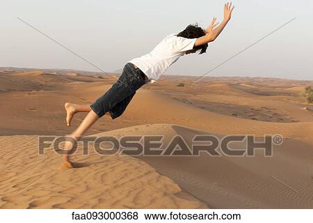 Teenage boy pretending to fall from top of desert sand dune View Large Photo Image Stock Photo - Teenage boy pretending to fall from top of desert sand dune. Fotosearch