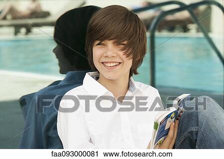 Stock Image - Teenage boy reading guidebook. Fotosearch