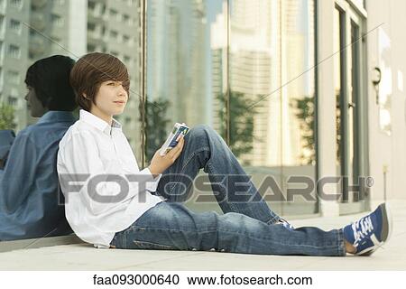 Teenage boy sitting on ground reading guidebook View Large Photo Image Stock Image - Teenage boy sitting on ground reading guidebook. Fotosearch