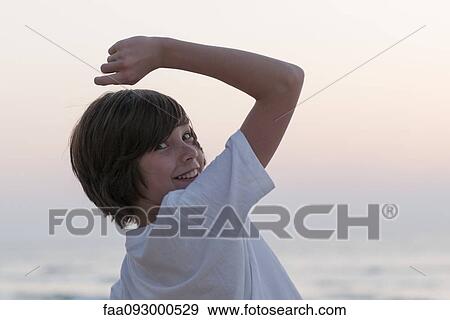 Stock Photo - Teenage boy smiling over shoulder, portrait. Fotosearch