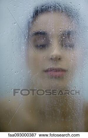 Stock Photo - Woman behind wet glass, eyes closed, close-up. Fotosearch