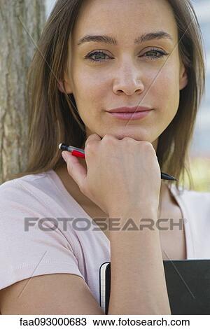 Woman holding diary, hand under chin, portrait View Large Photo Image Stock Image - Woman holding diary, hand under chin, portrait. Fotosearch
