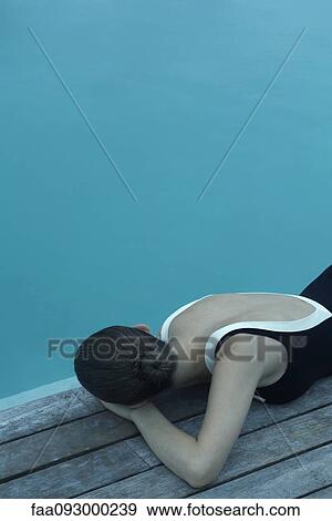 Woman in bathing suit lying on deck next to pool View Large Photo Image Stock Photo - Woman in bathing suit lying on deck next to pool. Fotosearch