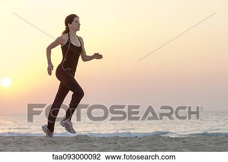 Woman jogging on beach at sunrise with earphones View Large Photo Image Stock Image - Woman jogging on beach at sunrise with earphones. Fotosearch