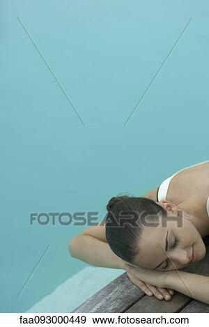 Woman lying next to pool, resting head on arms, eyes closed View Large Photo Image Stock Photo - Woman lying next to pool, resting head on arms, eyes closed. Fotosearch