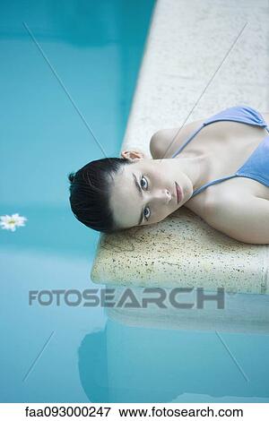 Stock Photo - Woman lying on floor next to pool. Fotosearch