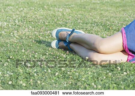 Stock Image - Woman lying on grass in summertime, cropped. Fotosearch