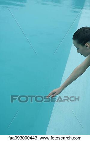 Stock Image - Woman reaching out, touching suface of water with hand. Fotosearch