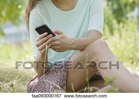 Stock Photo - Woman relaxing outdoors with smartphone. Fotosearch
