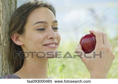 Woman sitting outdoors with apple View Large Photo Image Stock Photography - Woman sitting outdoors with apple. Fotosearch