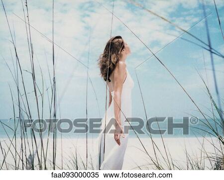 Woman standing at the beach with arms back, side view View Large Photo Image Stock Photography - Woman standing at the beach with arms back, side view. Fotosearch