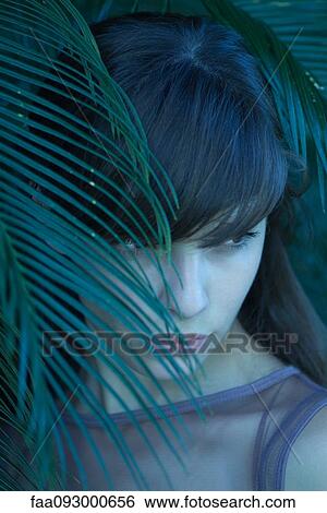 Woman standing behind leaves, looking away View Large Photo Image Stock Photograph - Woman standing behind leaves, looking away. Fotosearch