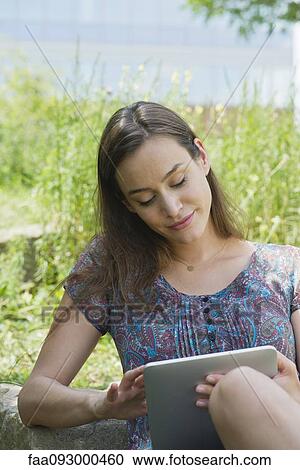 Stock Image - Woman using digital tablet outdoors. Fotosearch