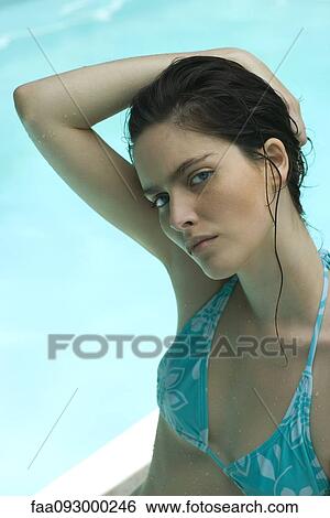 Stock Photograph - Woman wearing bikini holding wet hair up with hand. Fotosearch