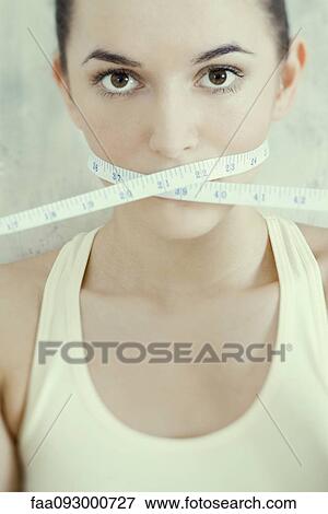 Stock Photo - Woman with measuring tape wrapped across mouth. Fotosearch