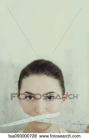 Woman with measuring tape wrapped across mouth View Large Photo Image Stock Photo - Woman with measuring tape wrapped across mouth. Fotosearch