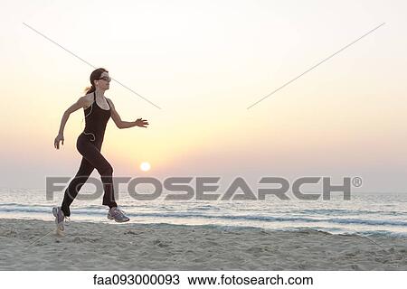 Woman with sunglasses jogging on beach at sunrise View Large Photo Image Stock Image - Woman with sunglasses jogging on beach at sunrise. Fotosearch