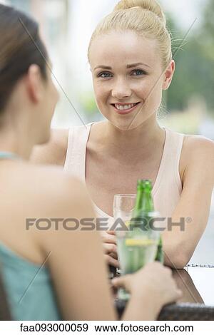 Stock Photo - Women chatting and having drinks outdoors. Fotosearch