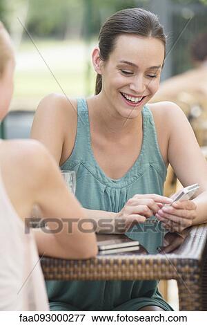 Stock Photo - Women chatting outdoors, one woman looking at smartphone. Fotosearch