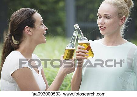 Women drinking together, clinking bottles View Large Photo Image Stock Image - Women drinking together, clinking bottles. Fotosearch