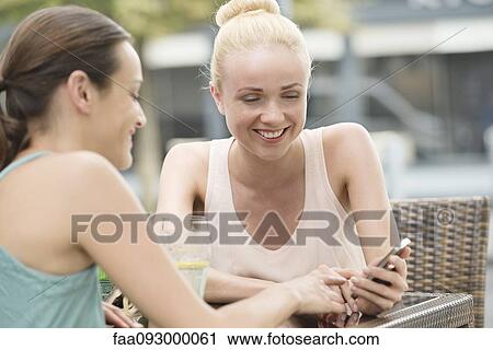 Women looking at smartphone outdoors View Large Photo Image Stock Image - Women looking at smartphone outdoors. Fotosearch