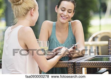 Women with smartphones at outdoor cafe View Large Photo Image Stock Photo - Women with smartphones at outdoor cafe. Fotosearch