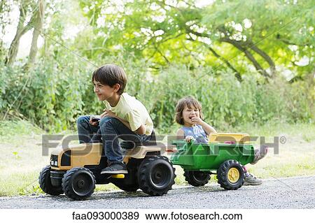 Young brother and sister riding on toy tractor View Large Photo Image Stock Photo - Young brother and sister riding on toy tractor. Fotosearch