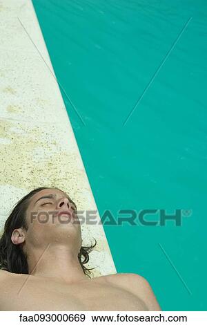 Young man lying on back beside pool View Large Photo Image Stock Photo - Young man lying on back beside pool. Fotosearch
