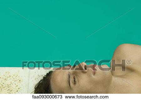 Stock Image - Young man resting next to pool, close-up. Fotosearch