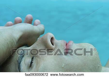 Young man touching forehead with back of hand, eyes closed, water in background View Large Photo Image Stock Image - Young man touching forehead with back of hand, eyes closed, water in background. Fotosearch