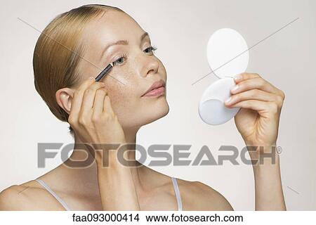 Picture - Young woman applying eyeliner. Fotosearch
