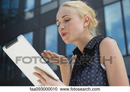 Young woman blowing kiss at digital tablet View Large Photo Image Stock Image - Young woman blowing kiss at digital tablet. Fotosearch