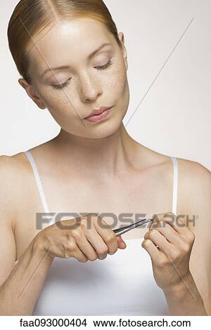 Picture - Young woman cutting cuticle. Fotosearch