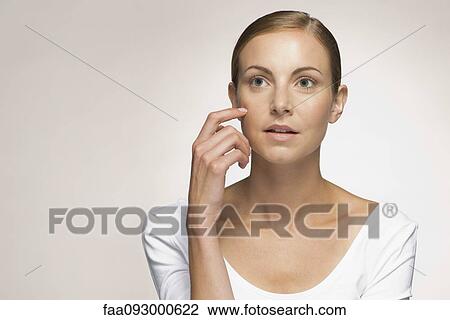 Young woman daydreaming, touching cheek, portrait View Large Photo Image Stock Image - Young woman daydreaming, touching cheek, portrait. Fotosearch
