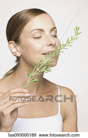 Stock Photo - Young woman enjoying frangrence of fresh rosemary. Fotosearch