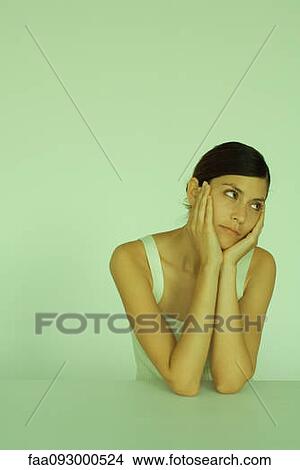 Picture - Young woman holding head, looking away, portrait. Fotosearch