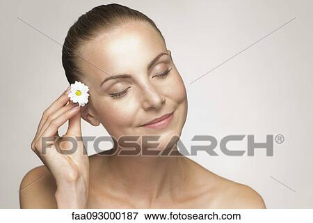 Young woman placing flower in hair View Large Photo Image Stock Photo - Young woman placing flower in hair. Fotosearch