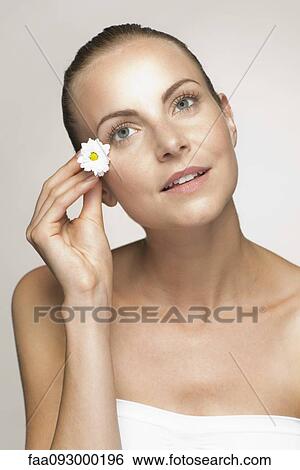 Stock Photograph - Young woman placing flower in hair. Fotosearch