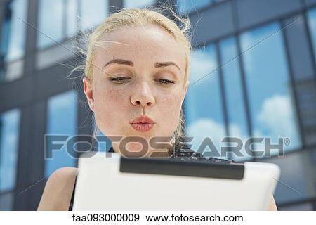 Stock Photo - Young woman puckering lips at digital tablet. Fotosearch