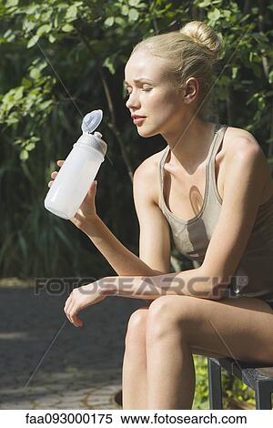 Young woman sitting outdoors with water bottle, eyes closed View Large Photo Image Stock Photography - Young woman sitting outdoors with water bottle, eyes closed. Fotosearch
